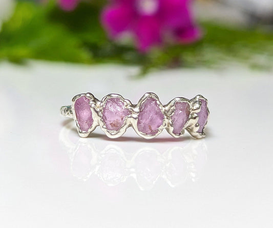 Raw pink sapphire eternity ring on handcrafted sterling silver band, perfect for gifts and special occasions.