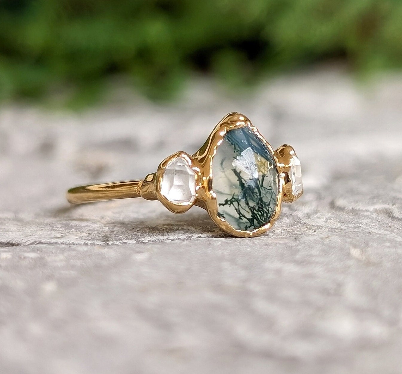 Moss Agate and Herkimer diamond engagement ring on gold band, featuring a pear shape Moss Agate and raw Herkimer diamonds.