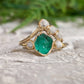 Raw Emerald and diamond Chevron wedding ring set on a natural stone background, featuring 18k Gold band.