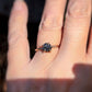 Raw black diamond engagement ring on hand, featuring 14k gold band and 7-8mm uncut black diamond.