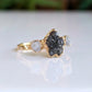 Raw uncut Black Diamond engagement ring on a gold band featuring two smaller raw diamonds.