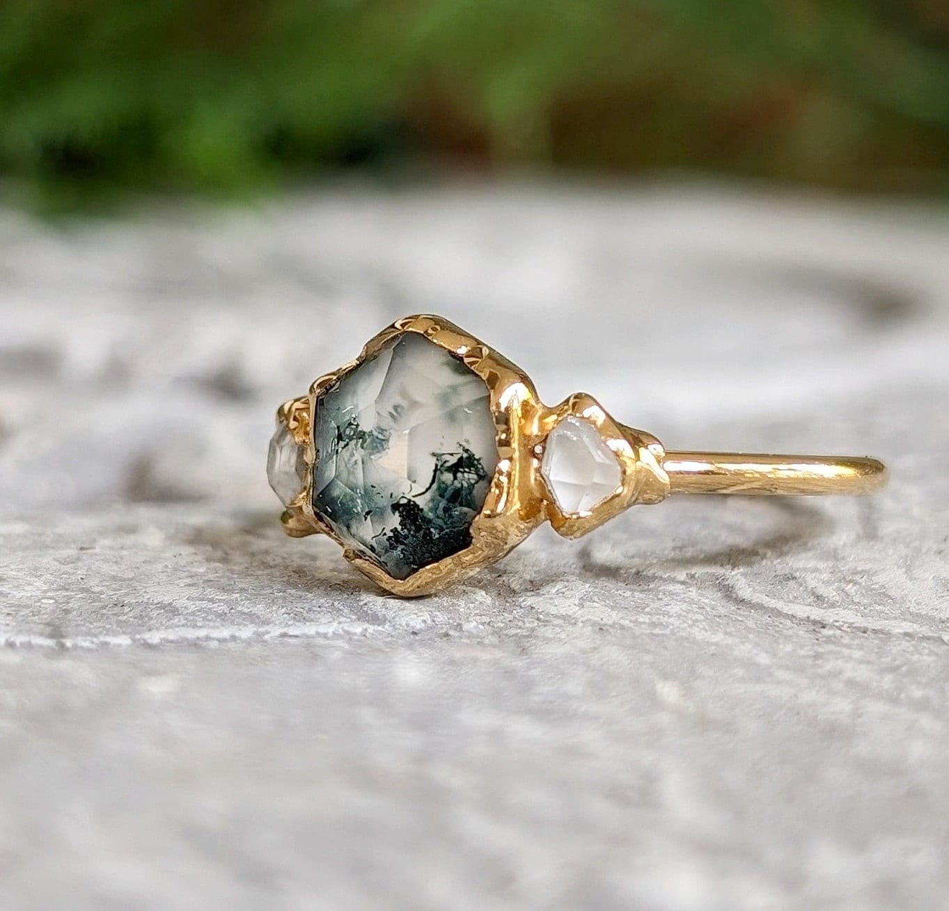 Moss Agate and Herkimer diamond engagement ring on a stone background, featuring a hexagon shape and 14k gold band.