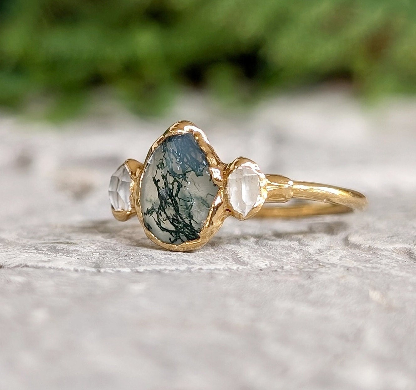 Moss Agate and Herkimer diamond engagement ring on gold band, featuring a pear-shaped agate and two raw diamonds.