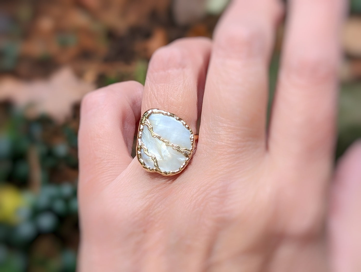 Handcrafted Mother of Pearl Kintsugi ring on a hand, featuring a unique design and gold-filled band.