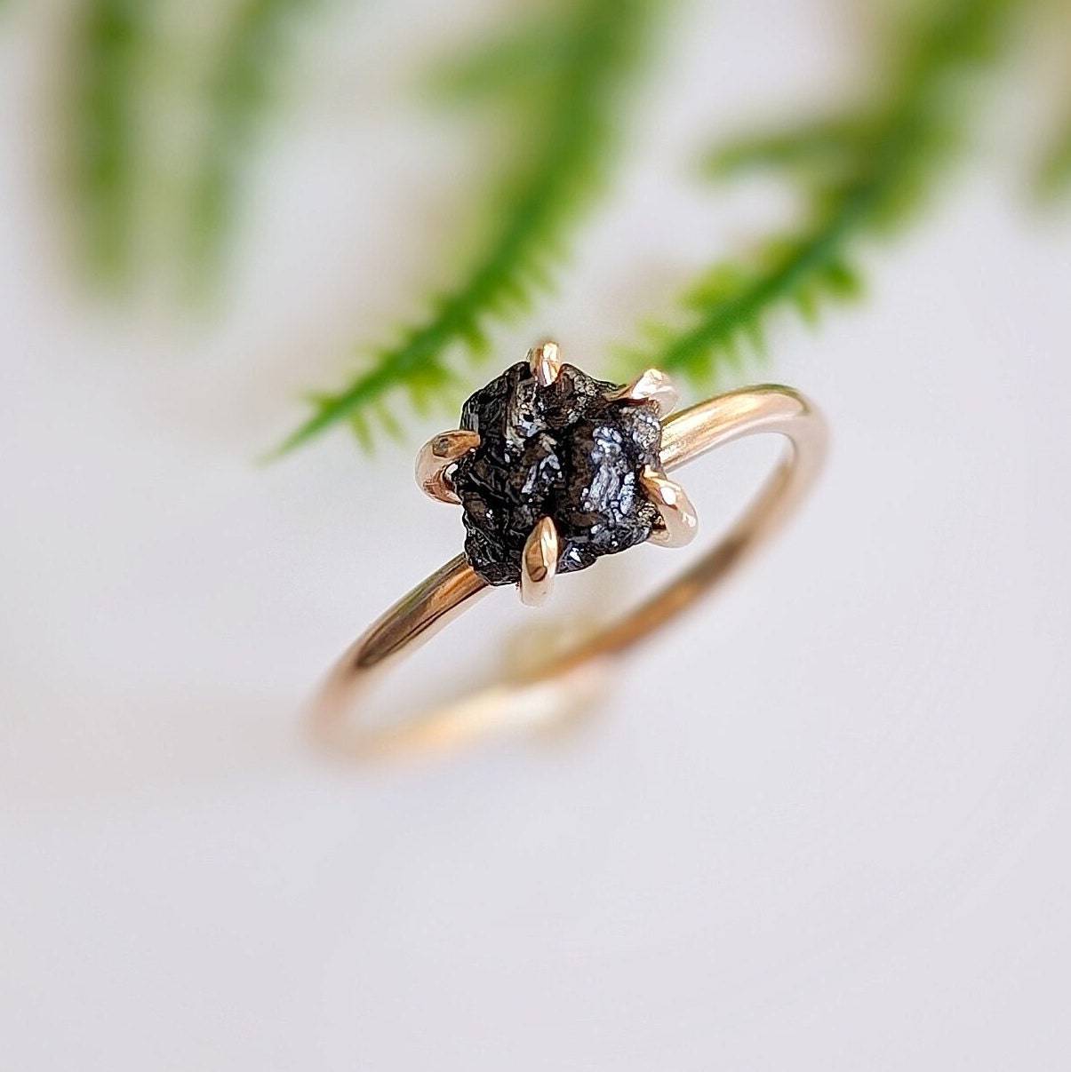 Raw black diamond engagement ring on 14k gold band featuring a rough uncut black diamond with a rustic design.