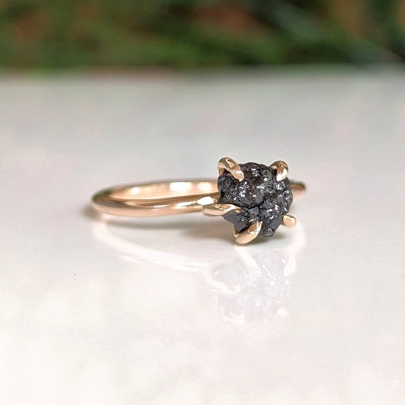 Raw black diamond engagement ring in solid 14k gold, showcasing a 7-8mm uncut diamond on a prong band.