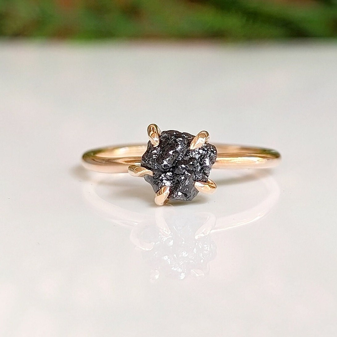 Raw black diamond engagement ring on a solid 14k gold band with prong settings, showcasing unique rustic elegance.