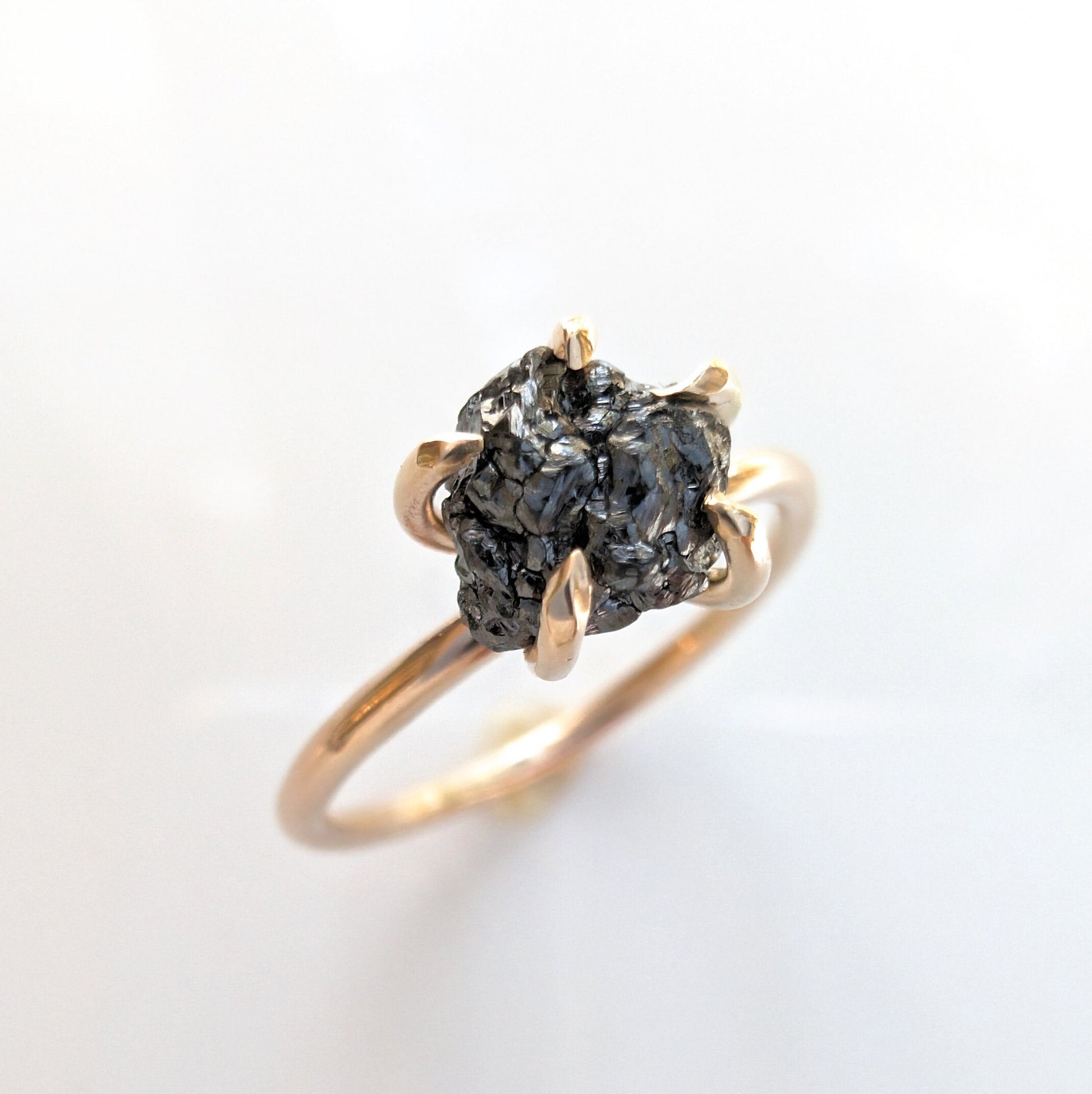 Raw black diamond engagement ring on solid 14k gold band, featuring a unique uncut black diamond.