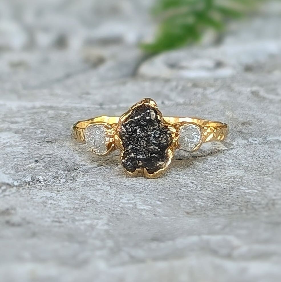 Unique raw uncut Black Diamond engagement ring on a solid 14k Gold band with smaller raw diamonds on either side.