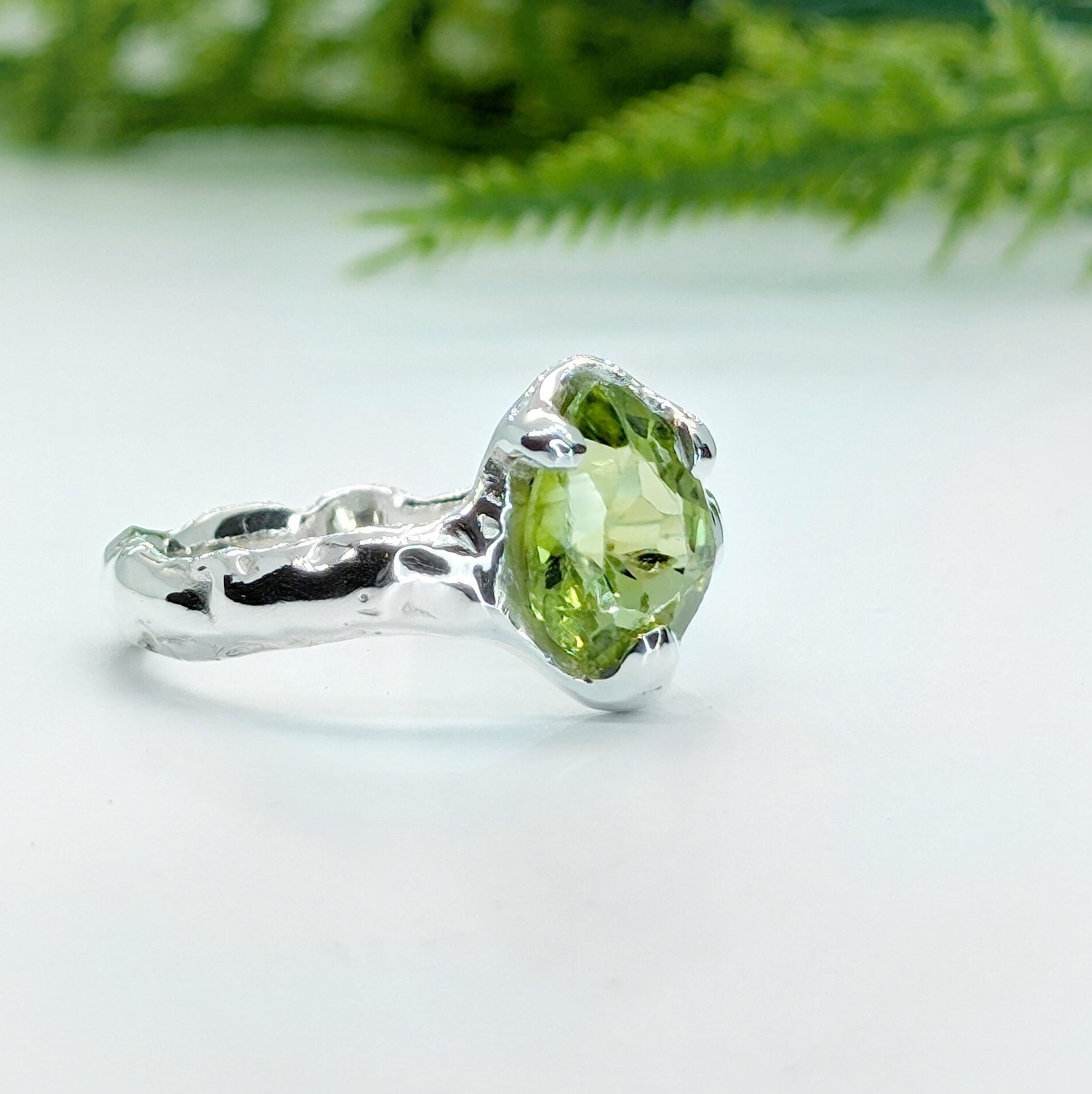 Handcrafted sterling silver ring featuring a rose cut Peridot gemstone, showcasing its organic textured band.