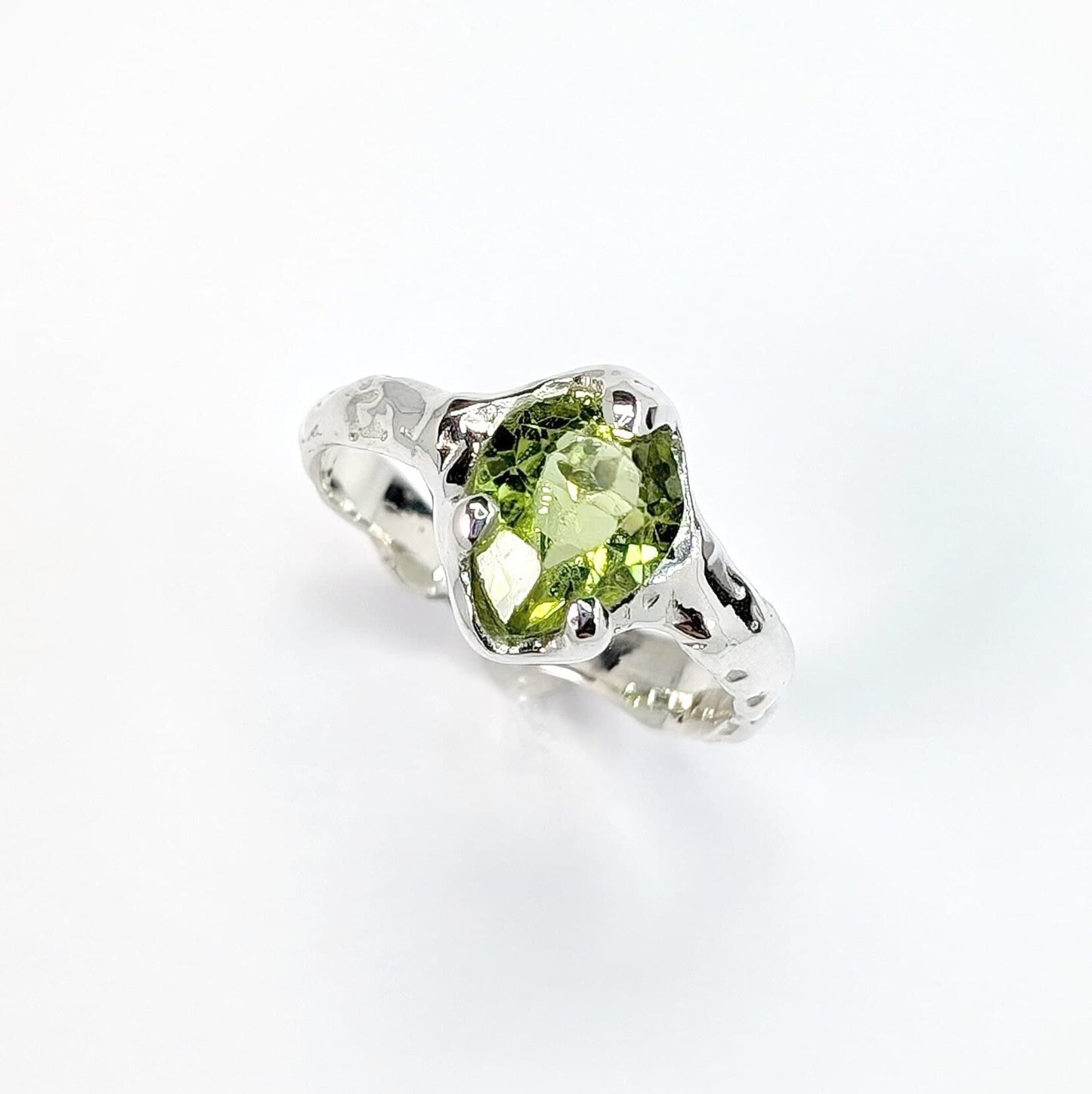 Solid 14k gold peridot ring featuring a unique organic textured band and striking green gemstone.