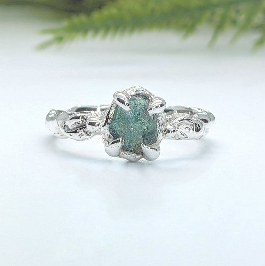 Raw Montana Sapphire silver ring with organic molten band, showcasing teal blue-green gemstone, perfect unique engagement ring.
