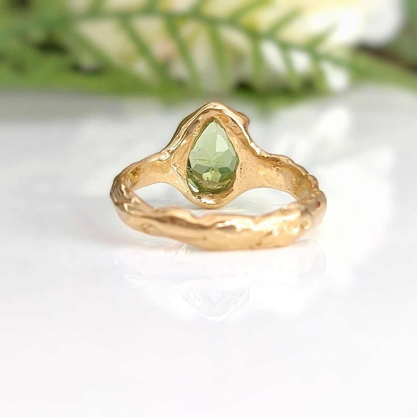 Handcrafted solid 14k gold peridot ring with organic textured band, capturing light beautifully.