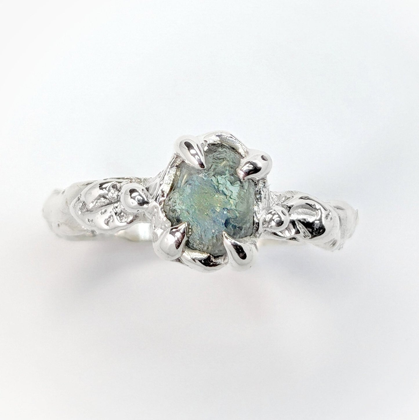 Raw Montana Sapphire ring in sterling silver, featuring a unique teal blue-green stone and an organic molten band.