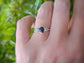 Raw black diamond engagement ring on hand, featuring a large uncut diamond and small accent stones on a silver band.