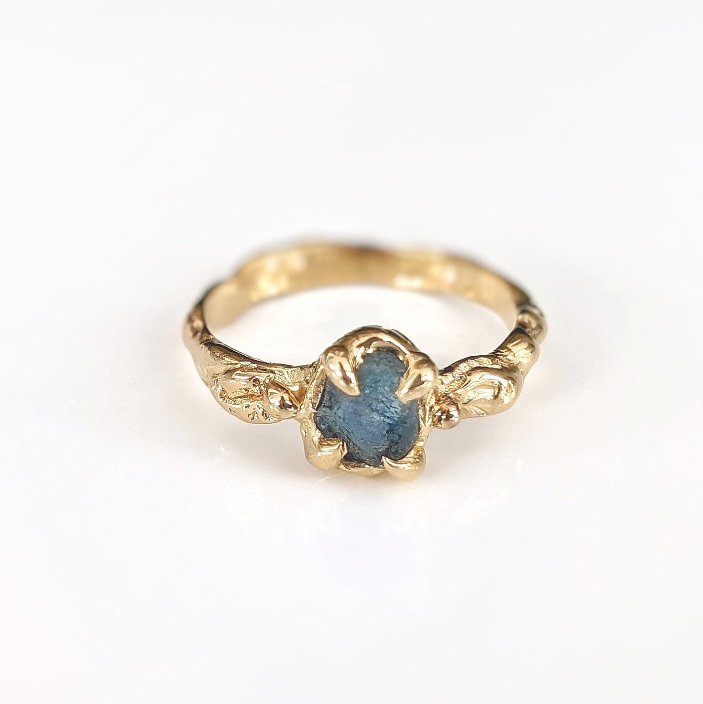 Raw Montana Sapphire engagement ring in solid 14k gold, featuring an organic textured band and unique teal stone.