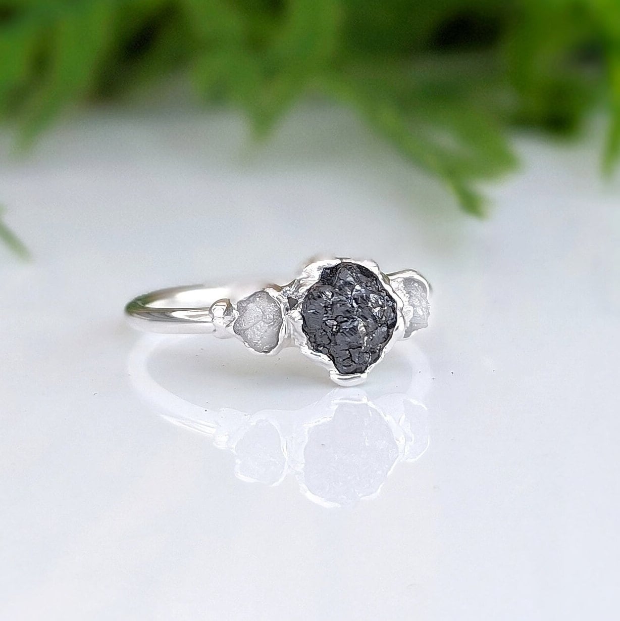 Raw black diamond engagement ring on a sterling silver band, featuring uncut black and smaller raw diamonds.