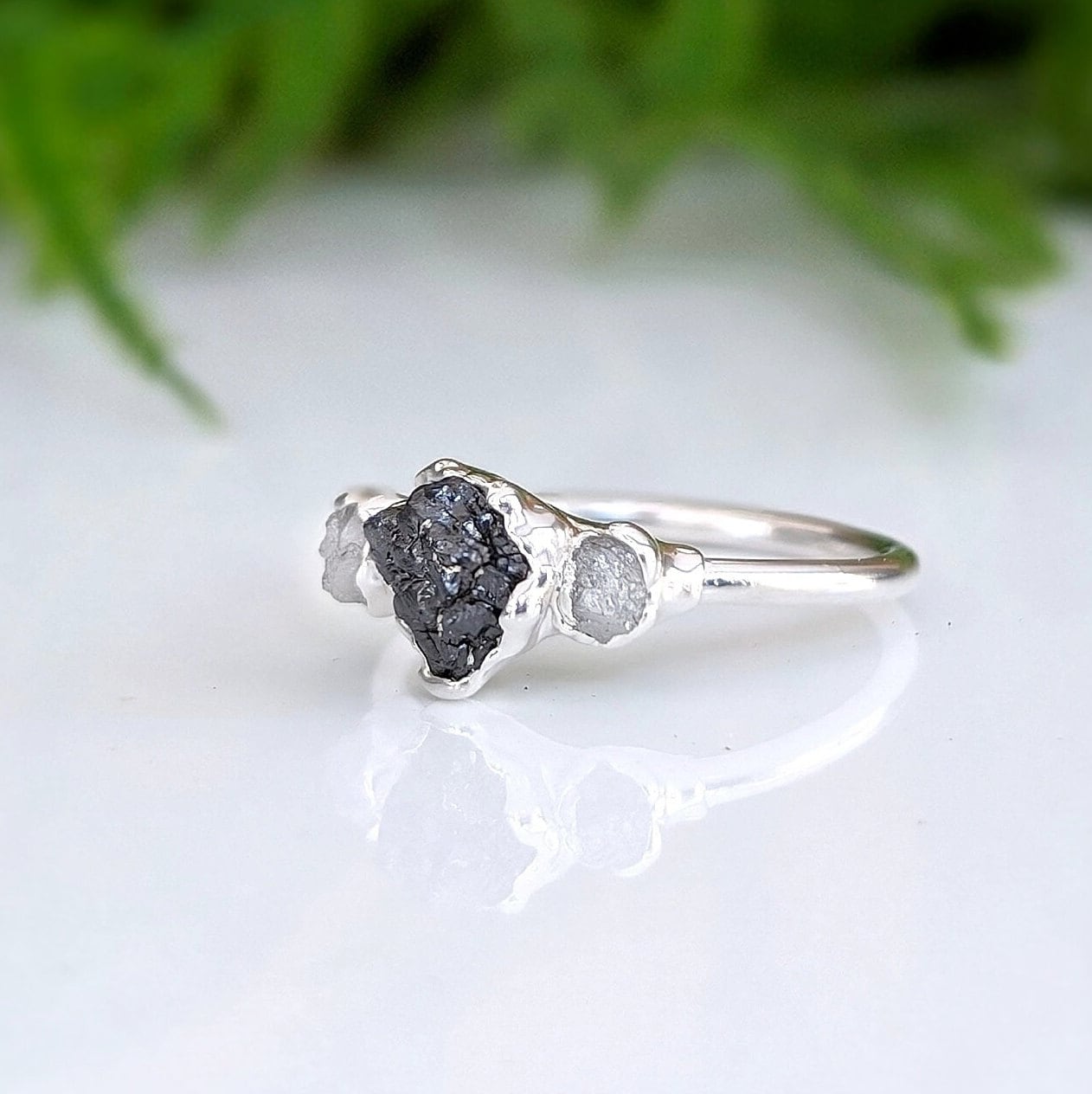Raw black diamond engagement ring with uncut black diamond and smaller raw diamonds on a sterling silver band.