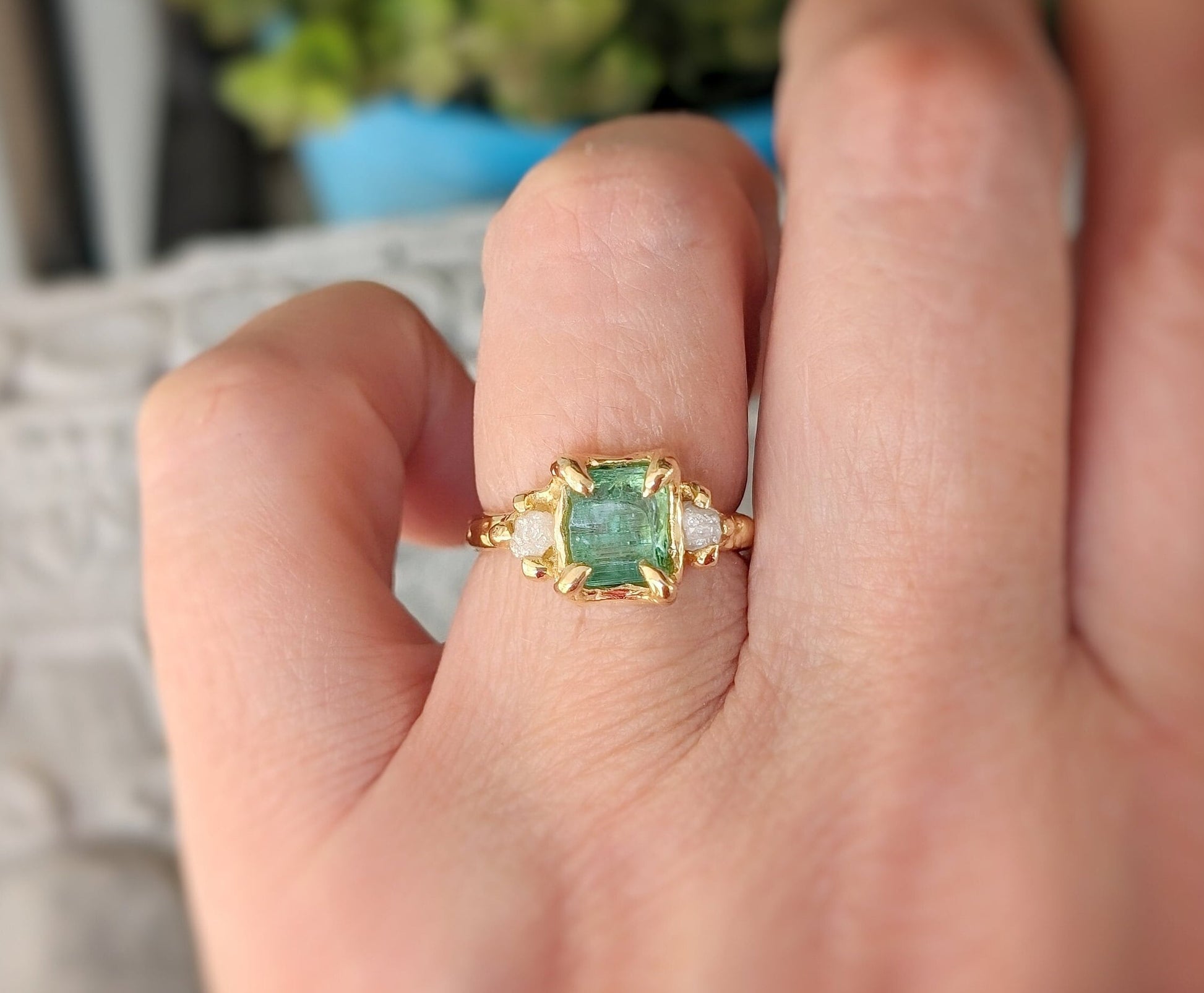 Raw Mint green Emerald and diamond engagement ring in gold on hand, showcasing elegant design and nature-inspired beauty.