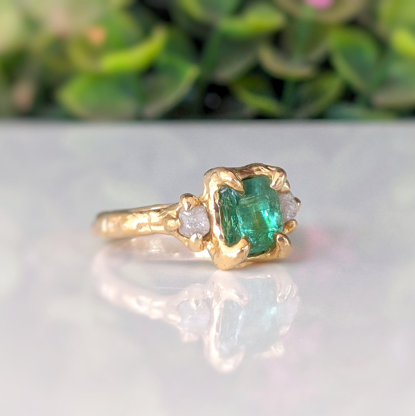 Raw emerald and diamond engagement ring in solid 14k gold, featuring a mint green emerald and two raw diamonds.