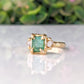 Raw Emerald engagement ring in gold, featuring a textured band and two small raw diamonds, showcasing nature-inspired beauty.