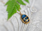 Labradorite Kintsugi necklace with gold plating on a textured background and green leaf.