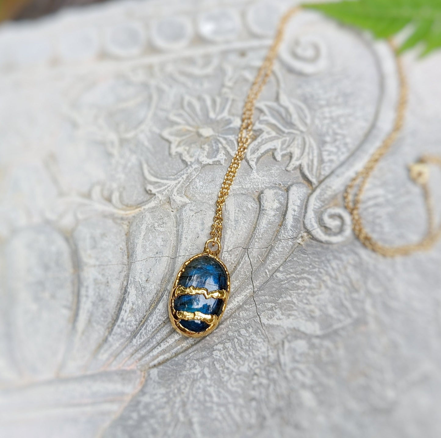 Labradorite Kintsugi necklace with gold plating and 21" chain, set against a textured stone background.
