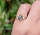 Lozenge shape Moss Agate engagement ring with Herkimer diamonds on 14k gold band, showcased on a hand.