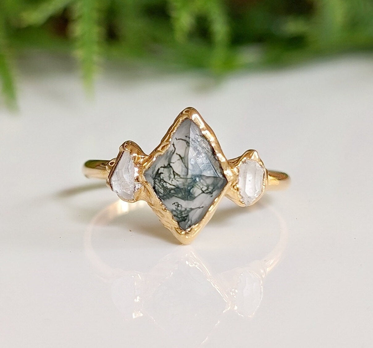 Moss Agate and Herkimer diamond engagement ring in lozenge shape set on a gold band, showcasing natural beauty.