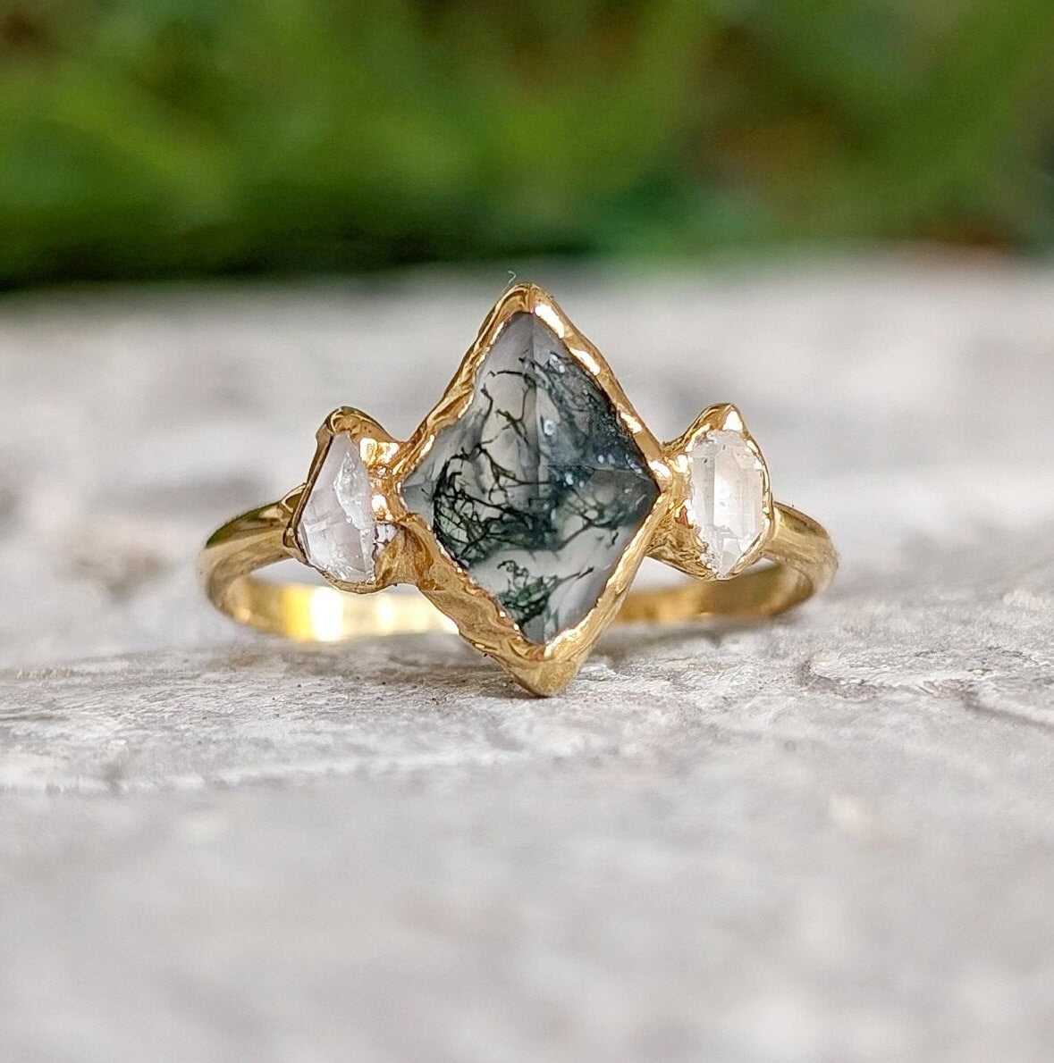 Lozenge-shaped Moss Agate engagement ring with Herkimer diamonds on a gold band, showcasing unique natural beauty.