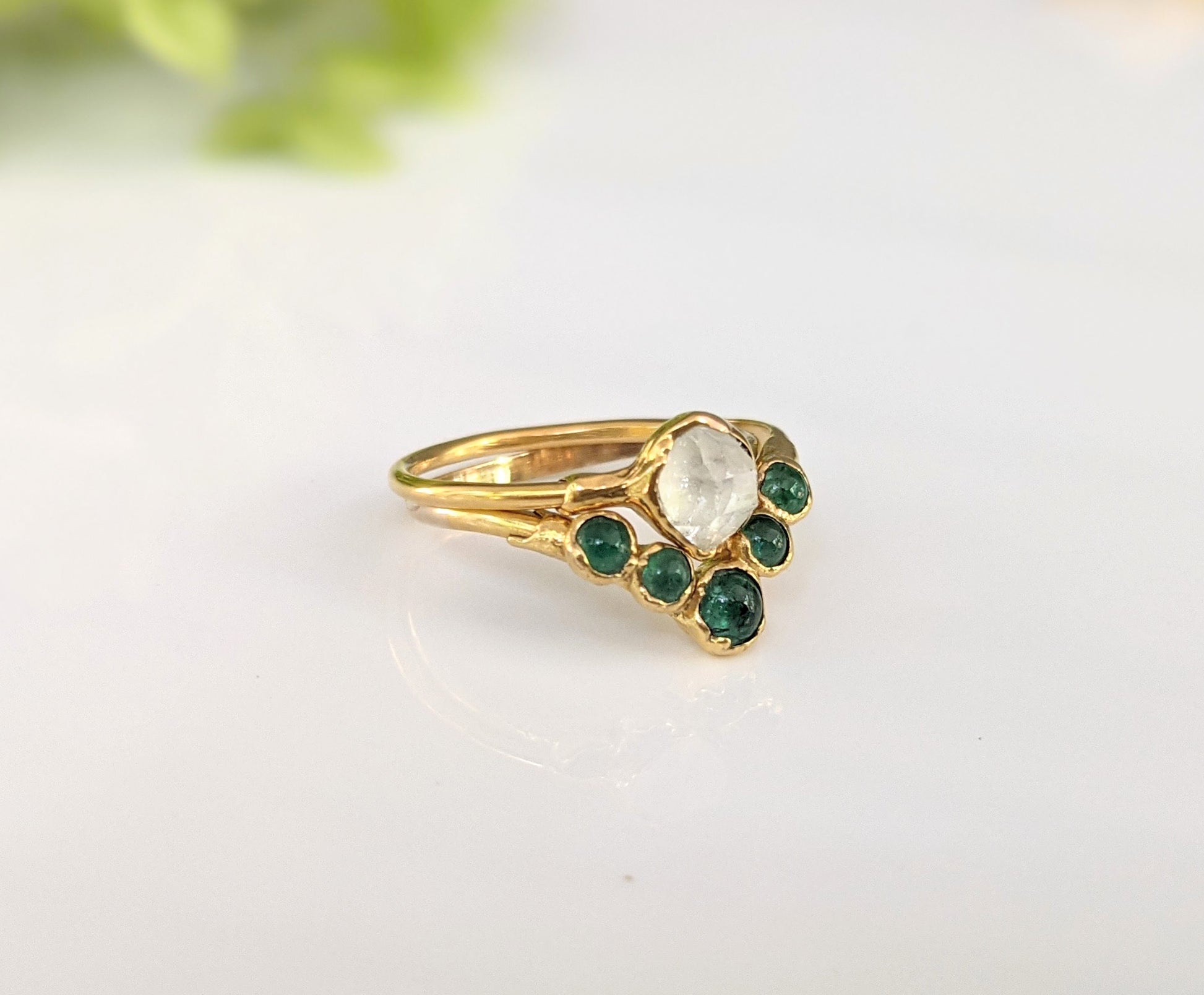 Natural emerald chevron wedding ring in 18k gold with a unique design featuring a central stone and emerald accents.