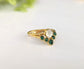 Natural emerald chevron wedding ring in 18k gold with a unique design featuring a central stone and emerald accents.