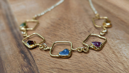 Personalized gold necklace featuring raw gemstones, square pendants, and elegant chain.