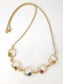 Personalized family birthstone necklace featuring raw gemstones in square settings with a gold chain.
