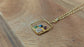 Personalized family birthstone necklace with raw gemstones and a gold square pendant on a chain.