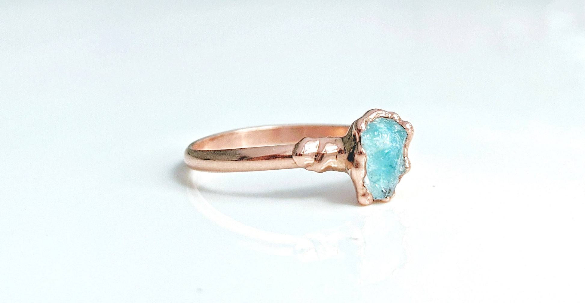 Raw Aquamarine eternity ring on a rose gold band, showcasing a natural 7-8mm gemstone in a unique electroformed design.