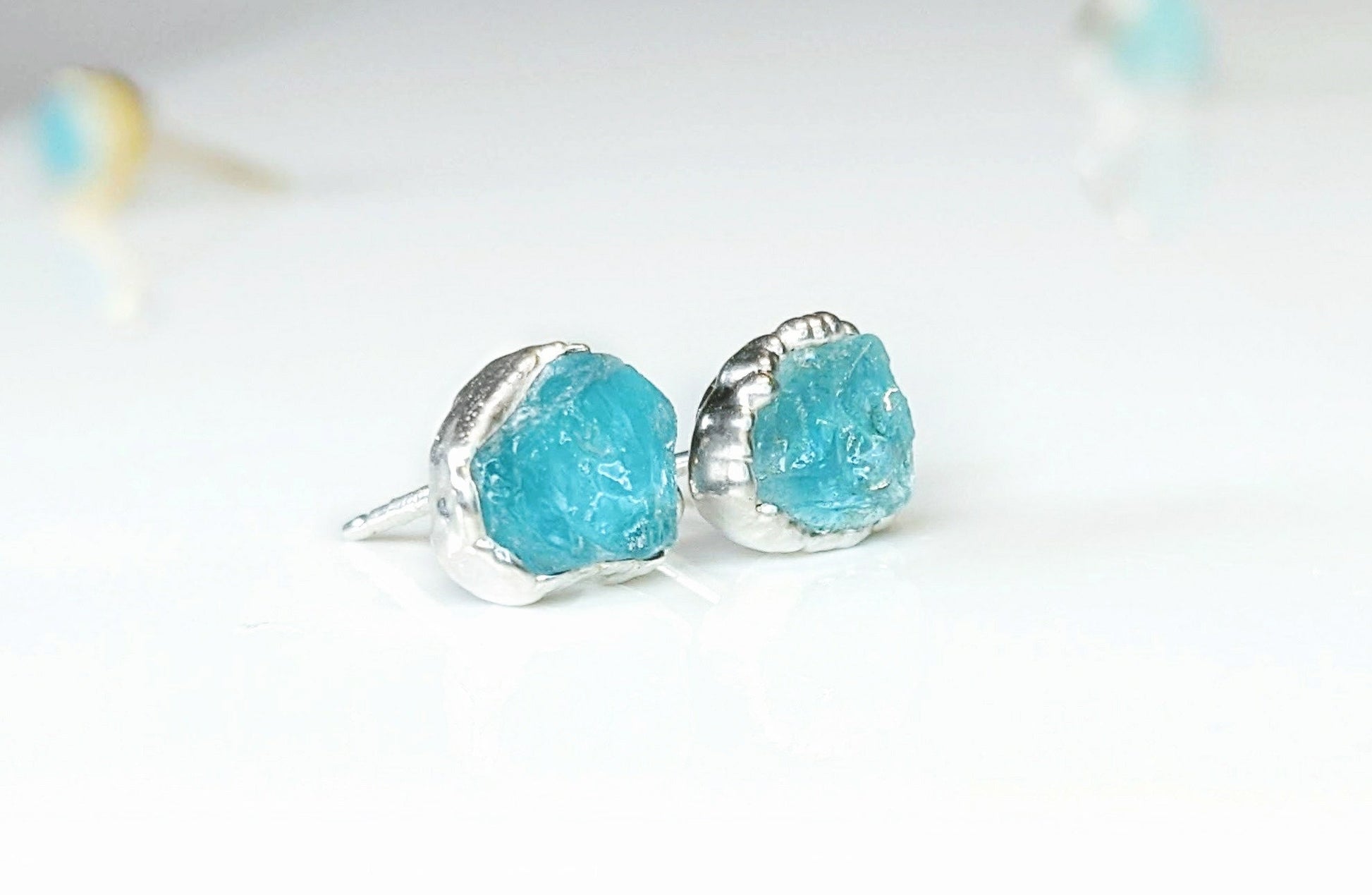 Dainty raw Aquamarine stud earrings set in silver, showcasing their rustic charm and unique textures.