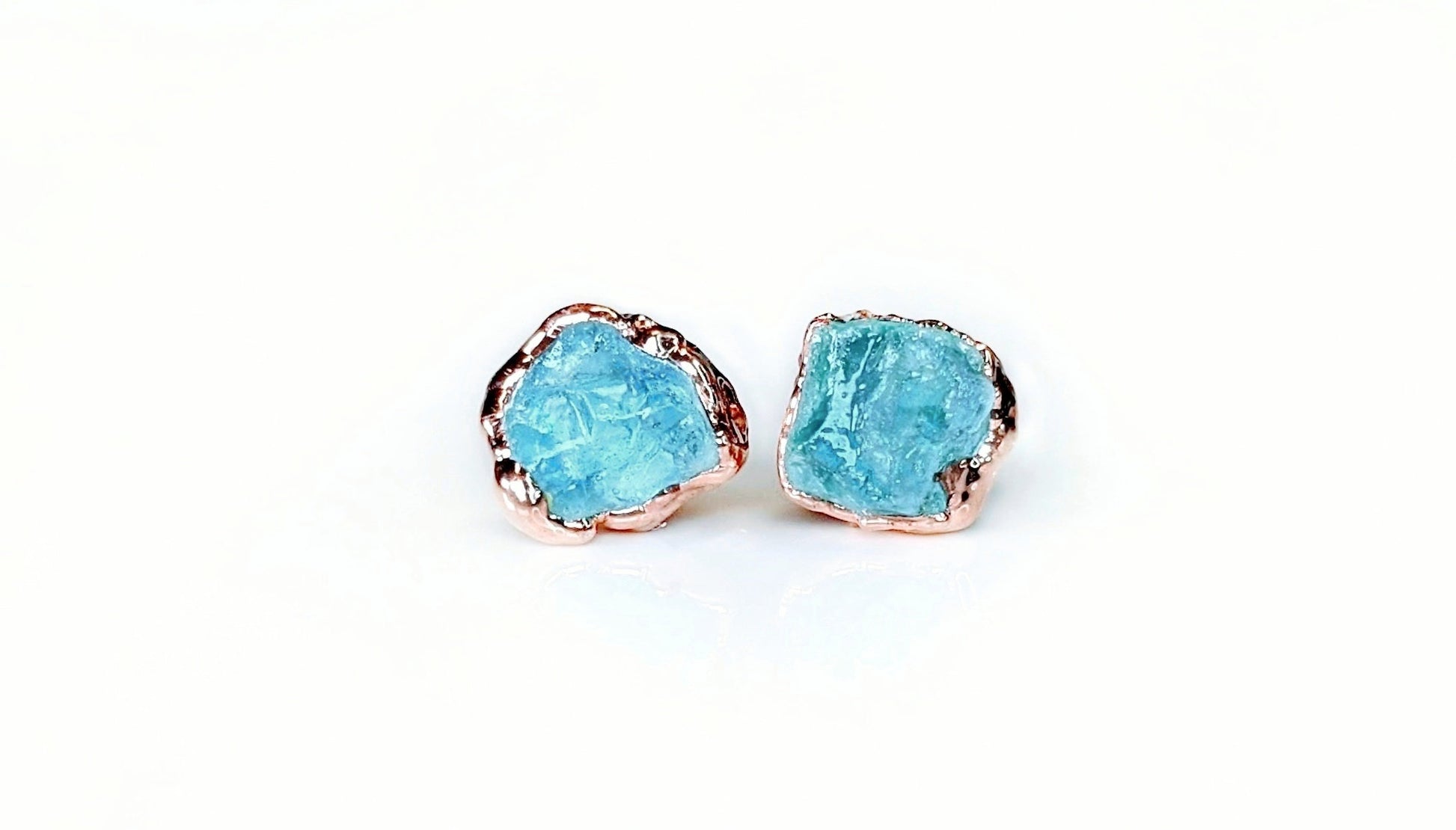 Dainty raw Aquamarine stud earrings in 18k gold electroformed setting, featuring unique blue gemstones.