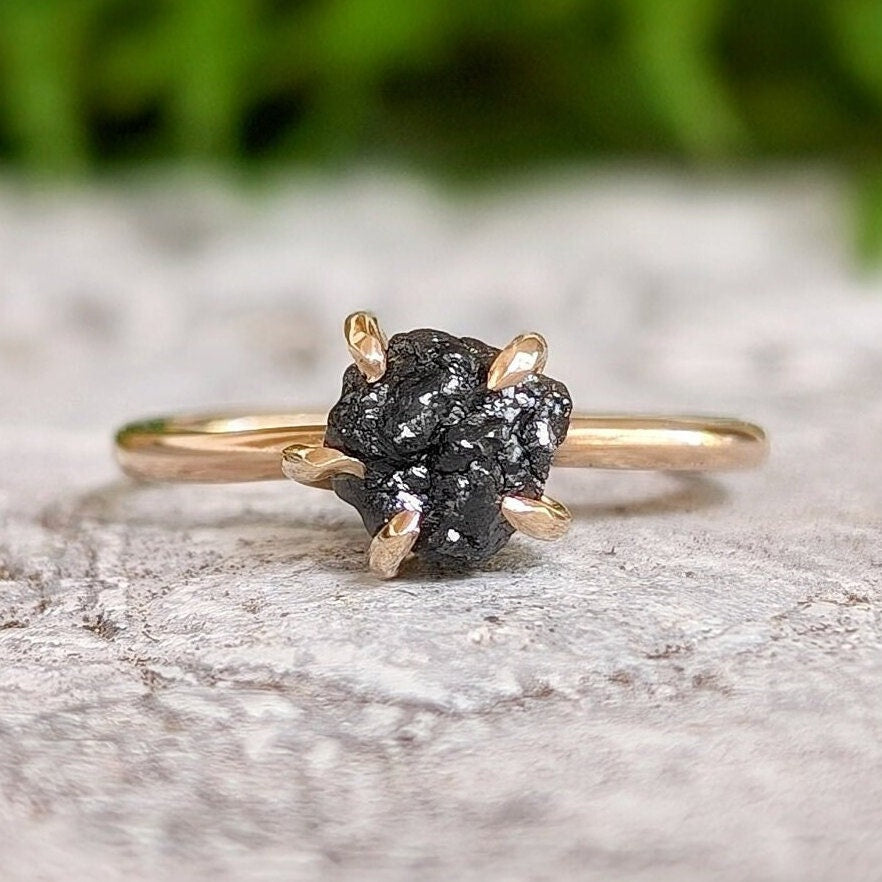 Raw black diamond engagement ring on a solid 14k gold band, featuring a unique rustic design.