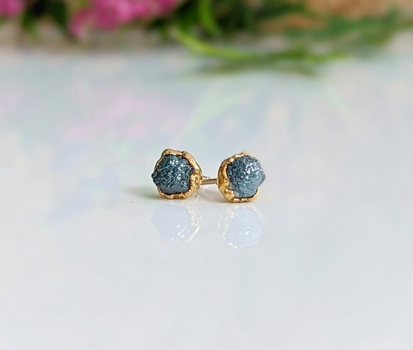 Raw blue diamond stud earrings with gold settings, perfect for bridal or casual wear, showcasing unique timeless beauty.