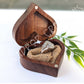 Heart-shaped wooden ring box with a raw diamond wedding ring set on a woven cushion.