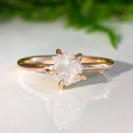 Raw diamond engagement ring with uncut diamond set in a rose gold band, symbolizing unique love and nature's beauty.
