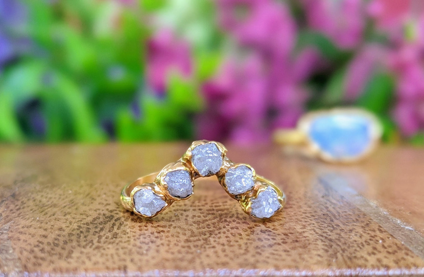 Raw diamond Chevron engagement ring in 18k gold with five conflict-free raw diamonds on a wooden surface.