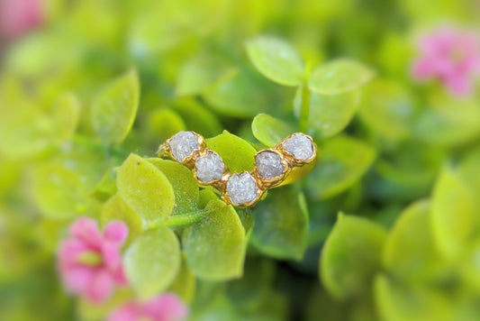 Raw diamond gold Chevron ring set among vibrant green leaves, showcasing unique handmade craftsmanship.