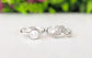 Raw diamond and Keshi pearl Chevron wedding ring set on a reflective surface with greenery in the background.