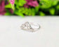 Handcrafted raw diamond Chevron wedding ring set on a polished surface with green foliage in the background.