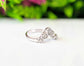 Chevron wedding ring featuring raw diamonds set in sterling silver, against a blurred floral background.