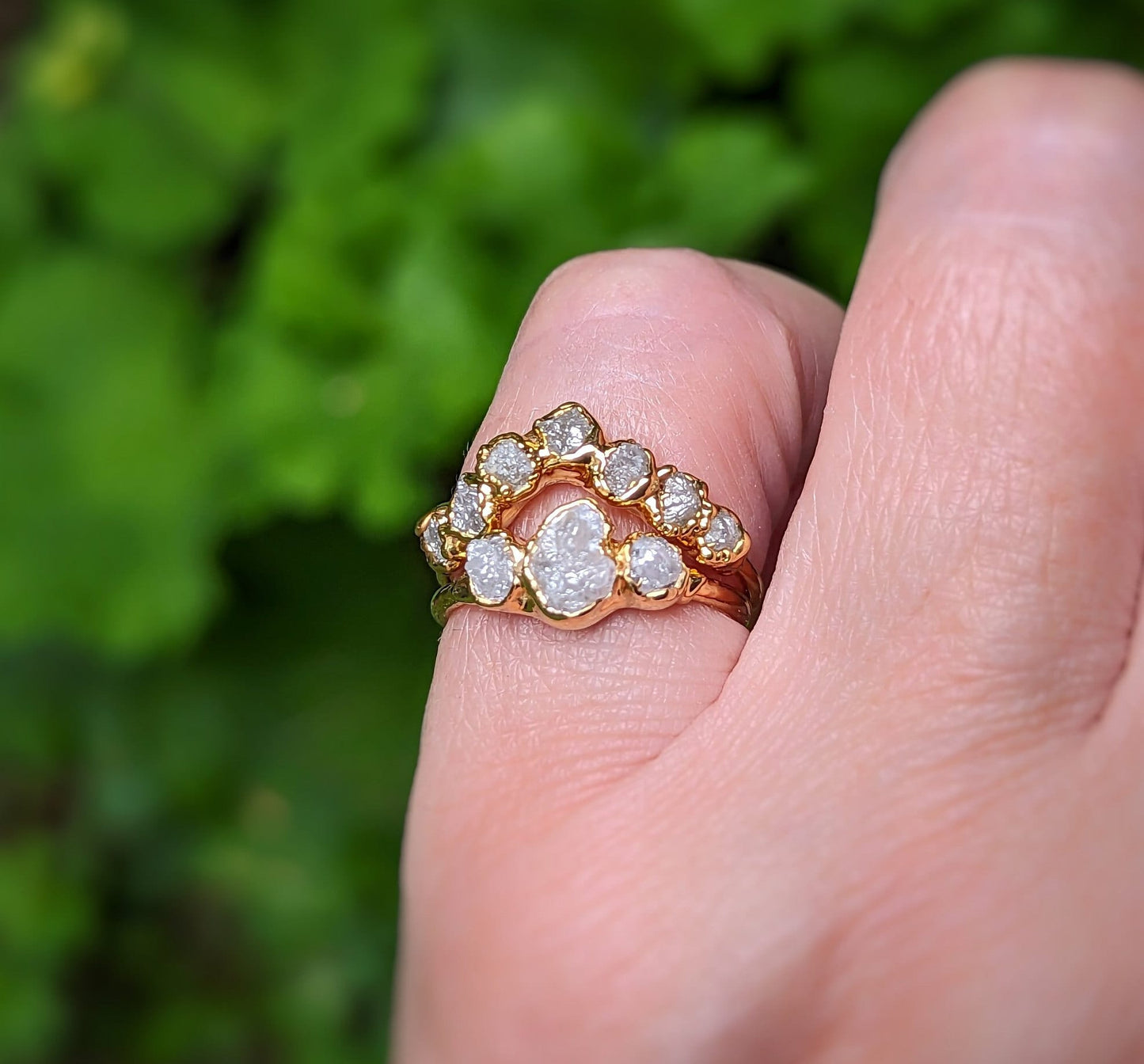 Raw diamond wedding ring set in solid 18k gold, featuring a unique design with multiple diamonds and a hand model.