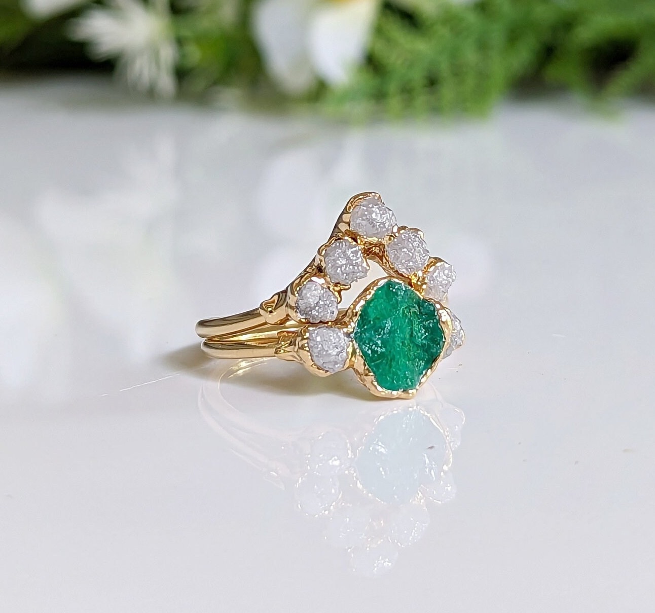 Raw emerald and diamond wedding ring set on gold band, featuring unique chevron design and conflict-free stones.