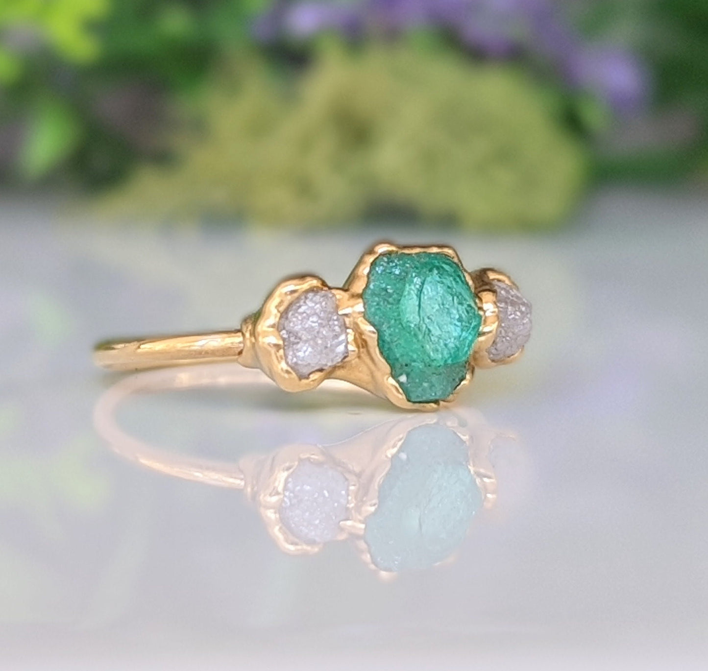 Raw emerald and diamond engagement ring with gold band, symbolizing love and commitment.
